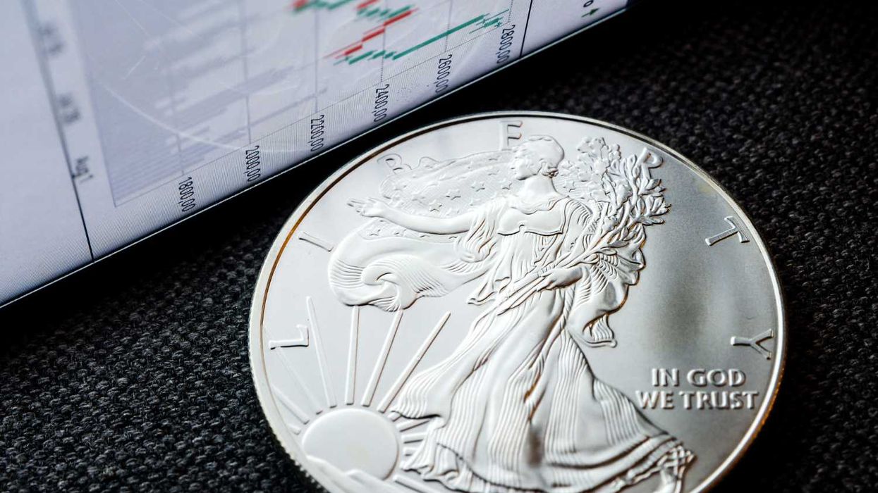 Silver coin beside a screen displaying stock market data.