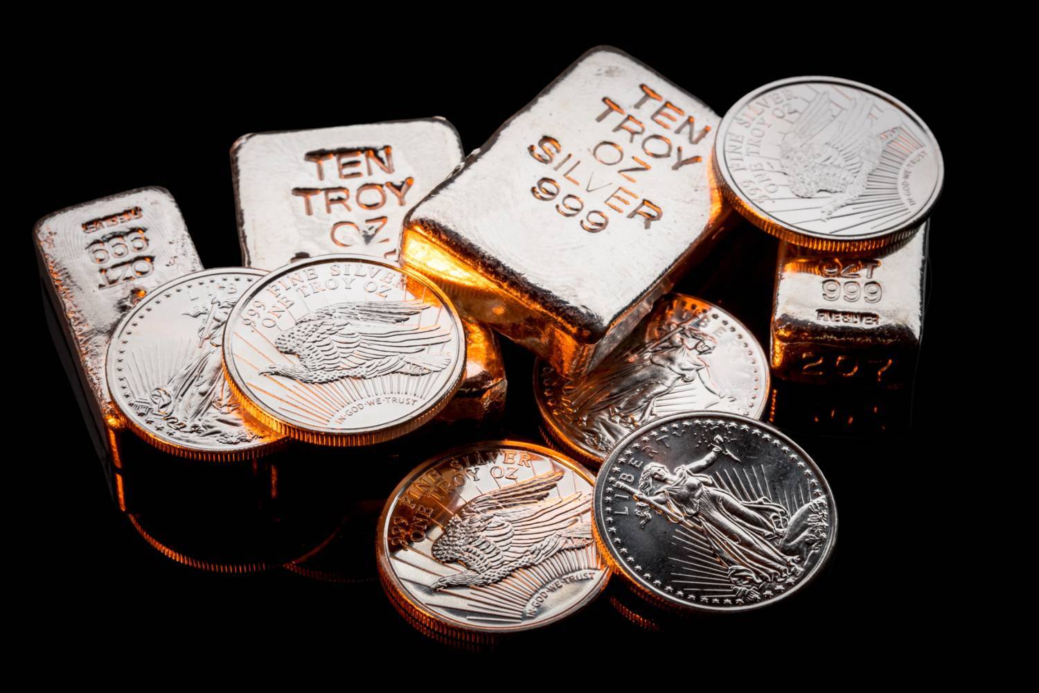 Silver coins and bars on a black background.