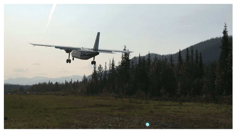 Small plane landing in a wooded area with mountains in the background at Flow Metals' Monster IOCG project