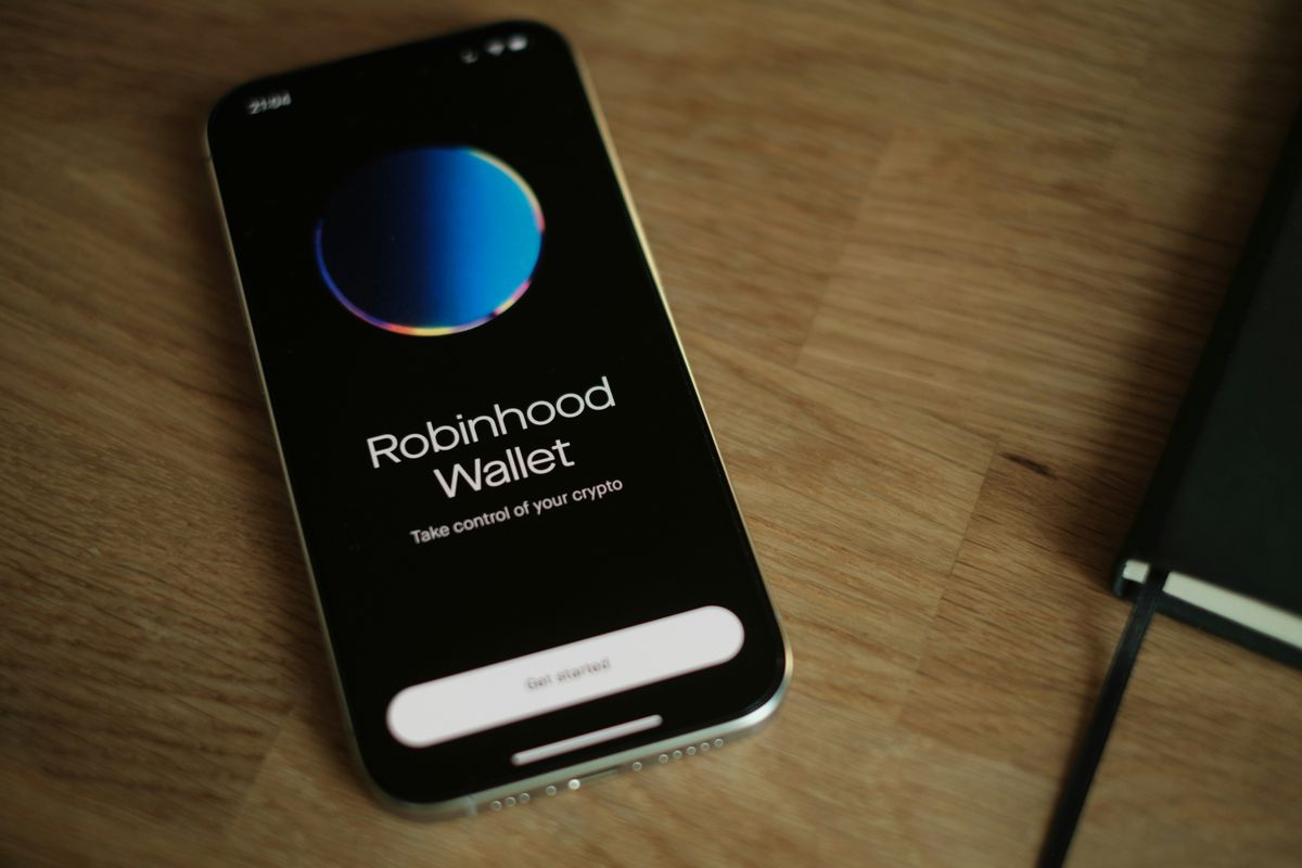 Smartphone displaying Robinhood Wallet app on a wooden table.