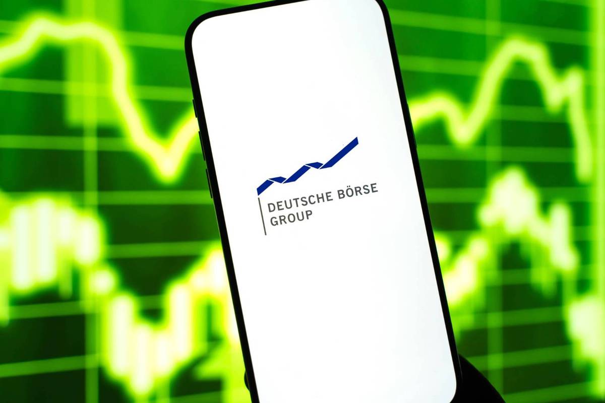 Smartphone displays the Deutsche Börse Group logo against a green background of stock market graphs.