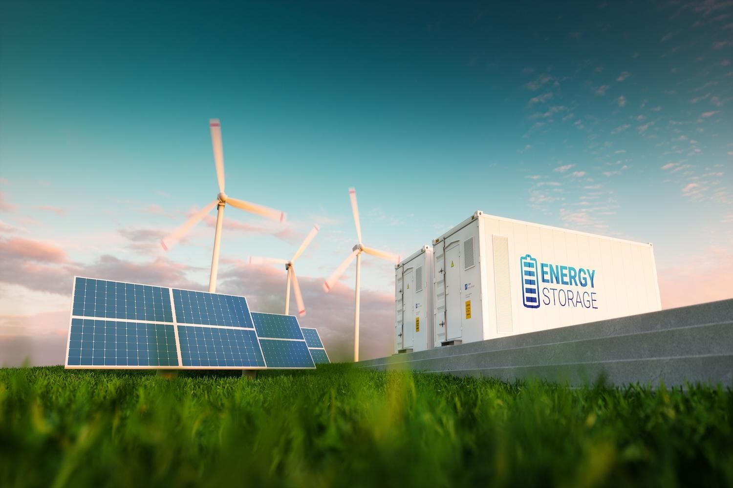Solar panels, wind turbines and an energy storage unit in a grassy field under a blue sky.