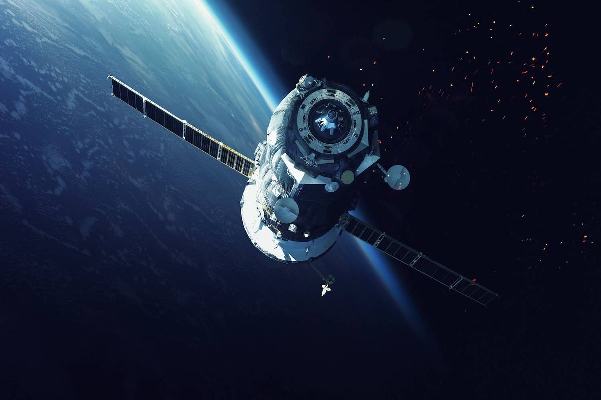 Spacecraft orbiting Earth with solar panels extended against a starry background.