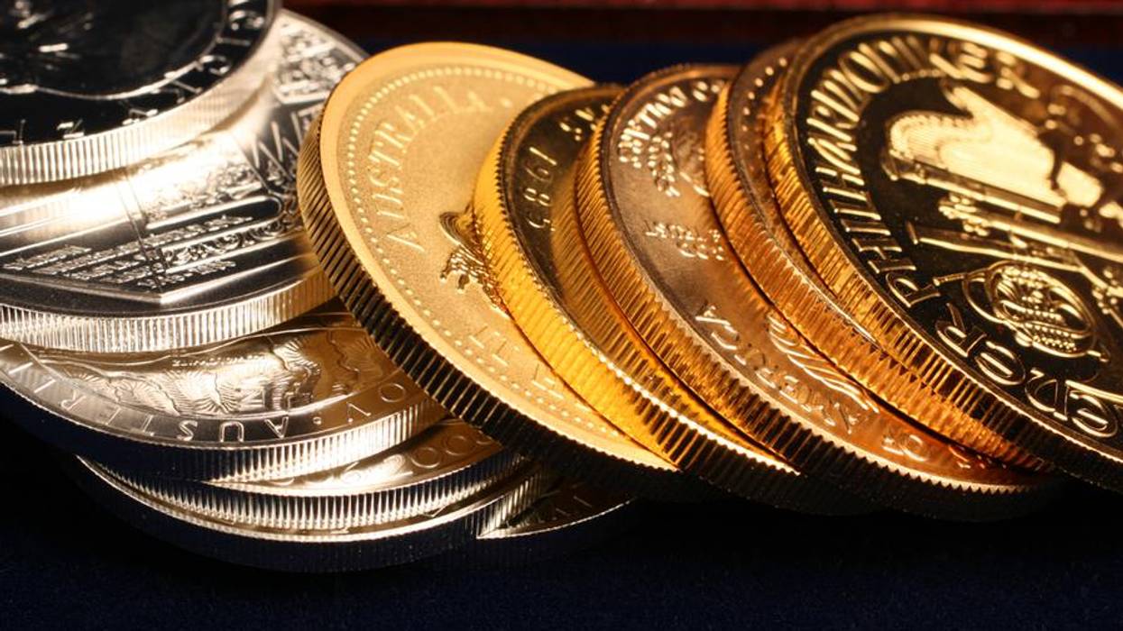 Stack of gold and silver commemorative coins on a dark surface.