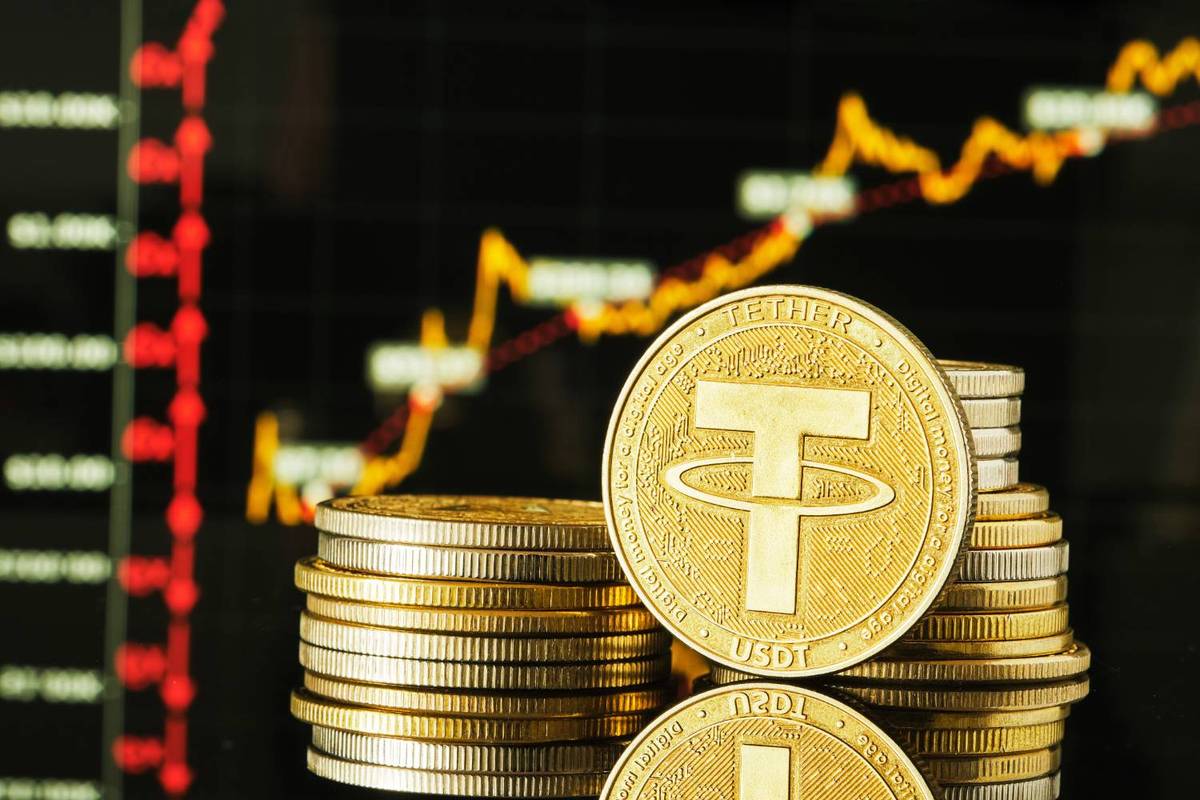 Stack of Tether coins displayed against background of rising gold and red financial graphs.