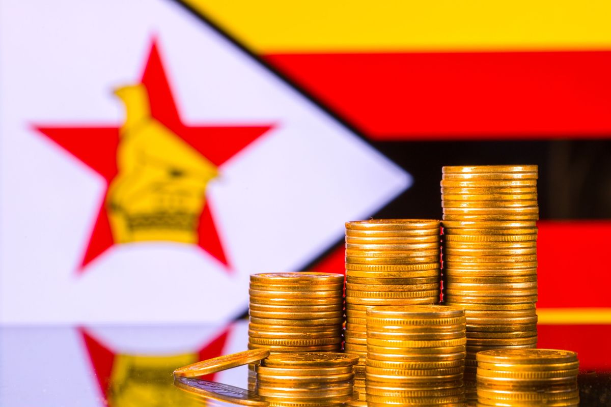 Stacks of gold coins in front of Zimbabwe's flag.