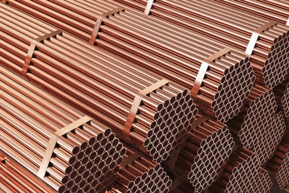 Stacks of shiny copper pipes bound with straps.