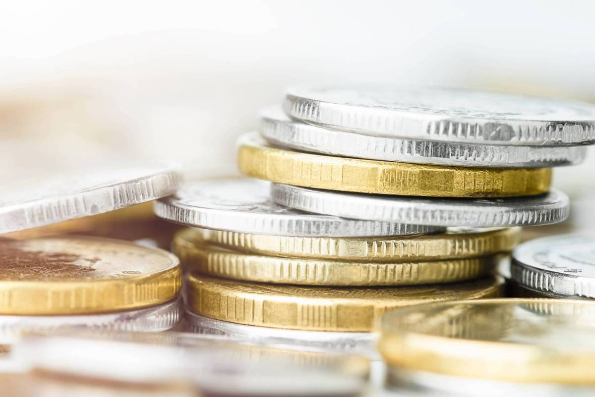 Stacks of silver and gold coins piled on a white surface, with a blurred background.