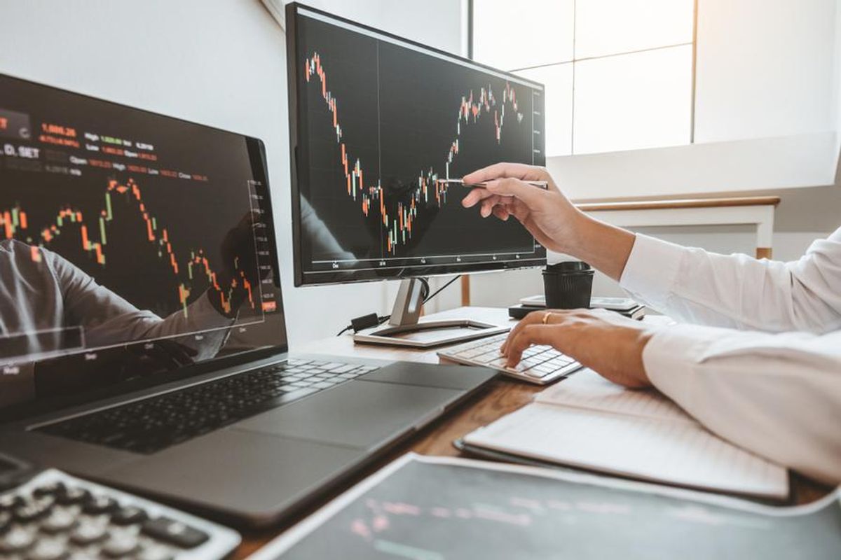 stock charts on two computer screens