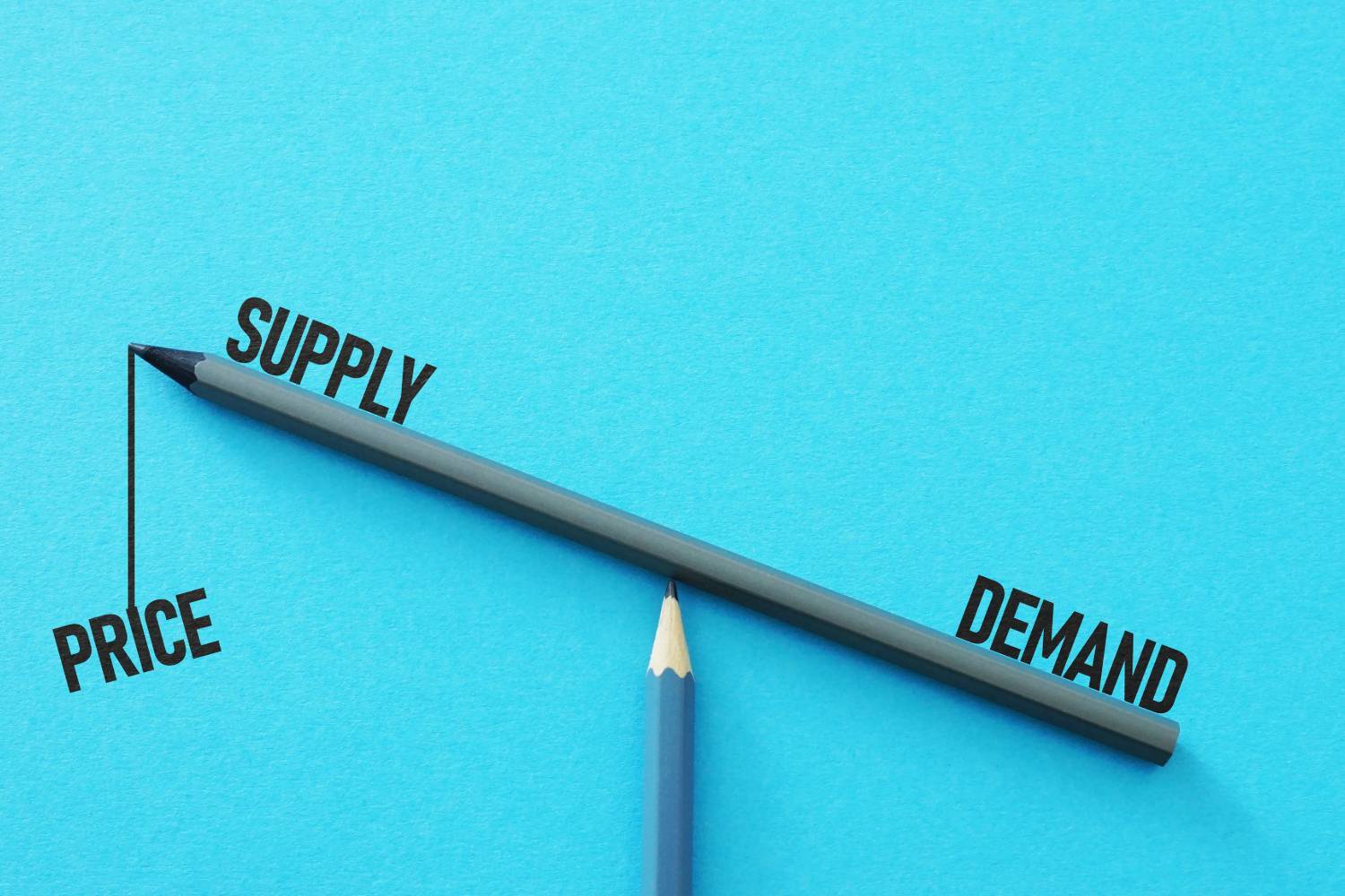 Supply/demand imbalance visualization using pencils on blue background.