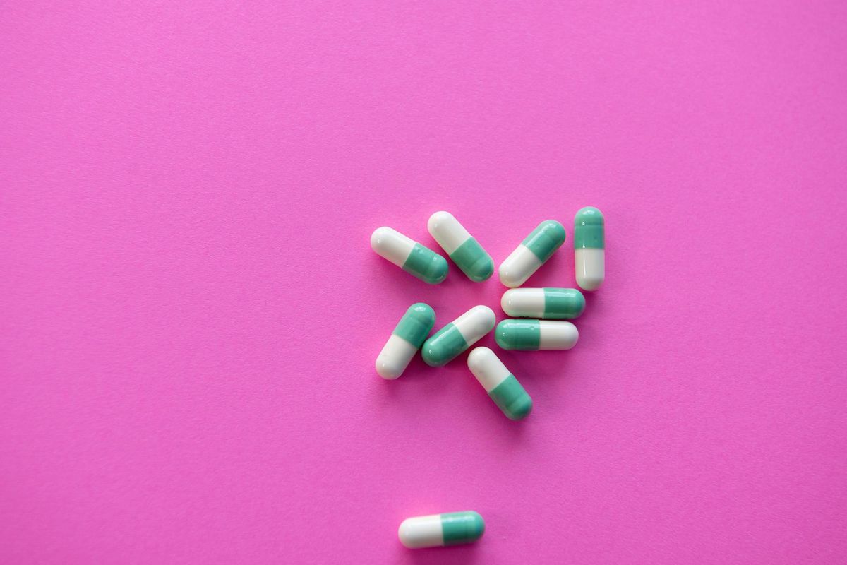 teal and white pills over pink background