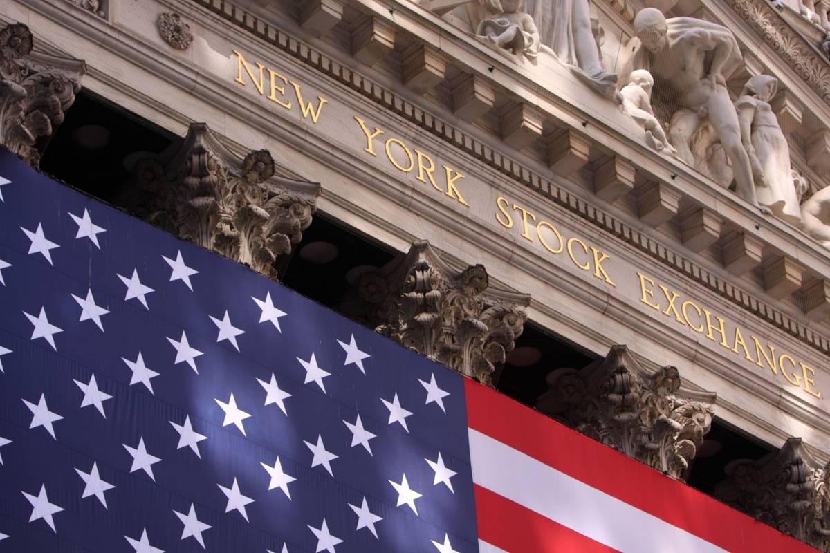 The American flag hangs in front of the ornate New York Stock Exchange building, text reads: New York Stock Exchange.