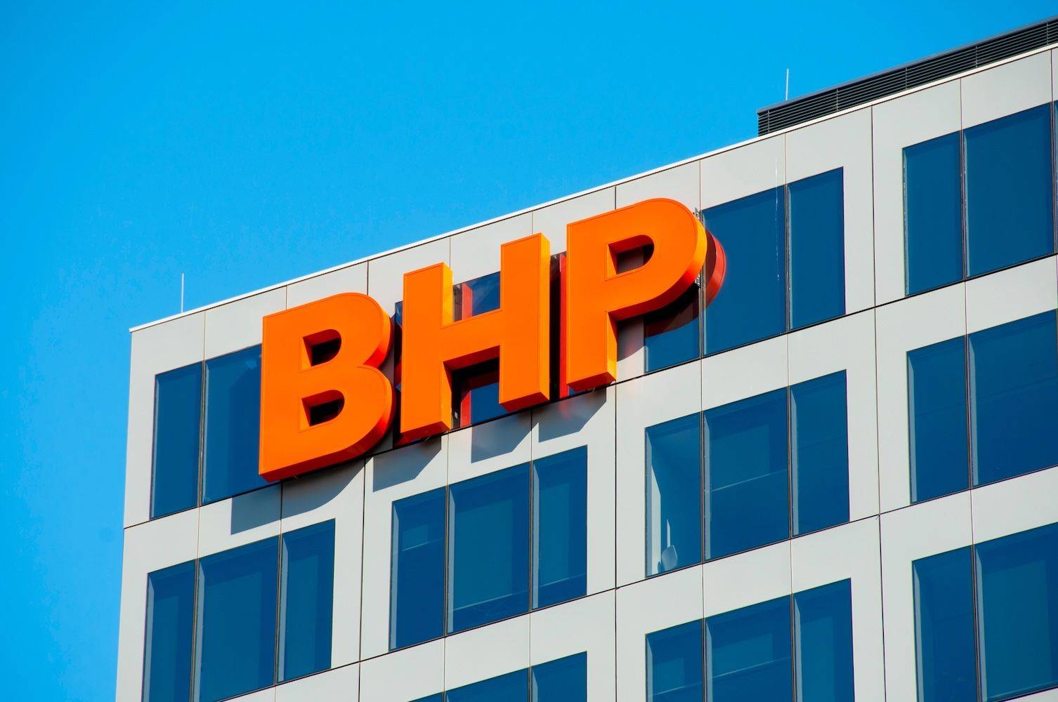 The building facade displays large orange letters "BHP" against a clear blue sky.