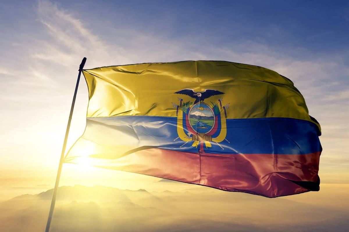 The Ecuadorian flag waves against a sunset backdrop, with mountains silhouetted on the horizon.