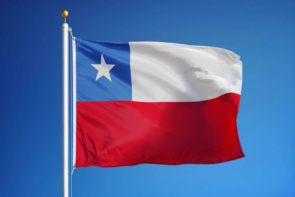 The flag of Chile with blue, white, red colors and a star waves against a clear blue sky.