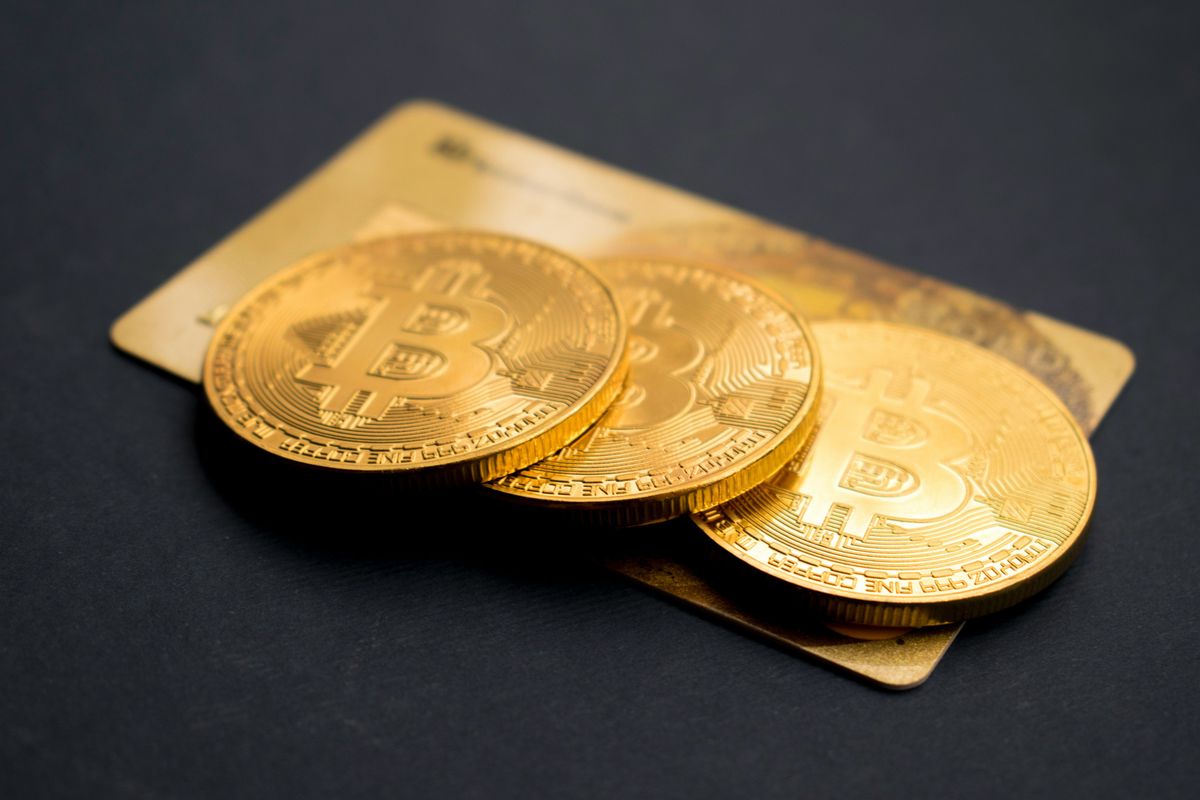 Three Bitcoin coins placed on a gold credit card.