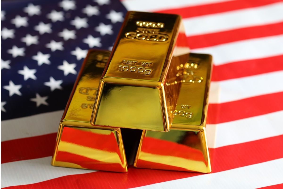 Three gold bullion bars on top of USA flag.