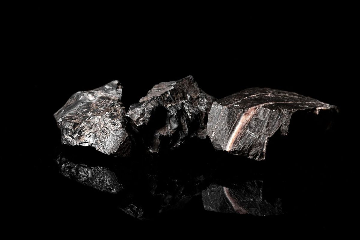 Three pieces of manganese ore on black background.