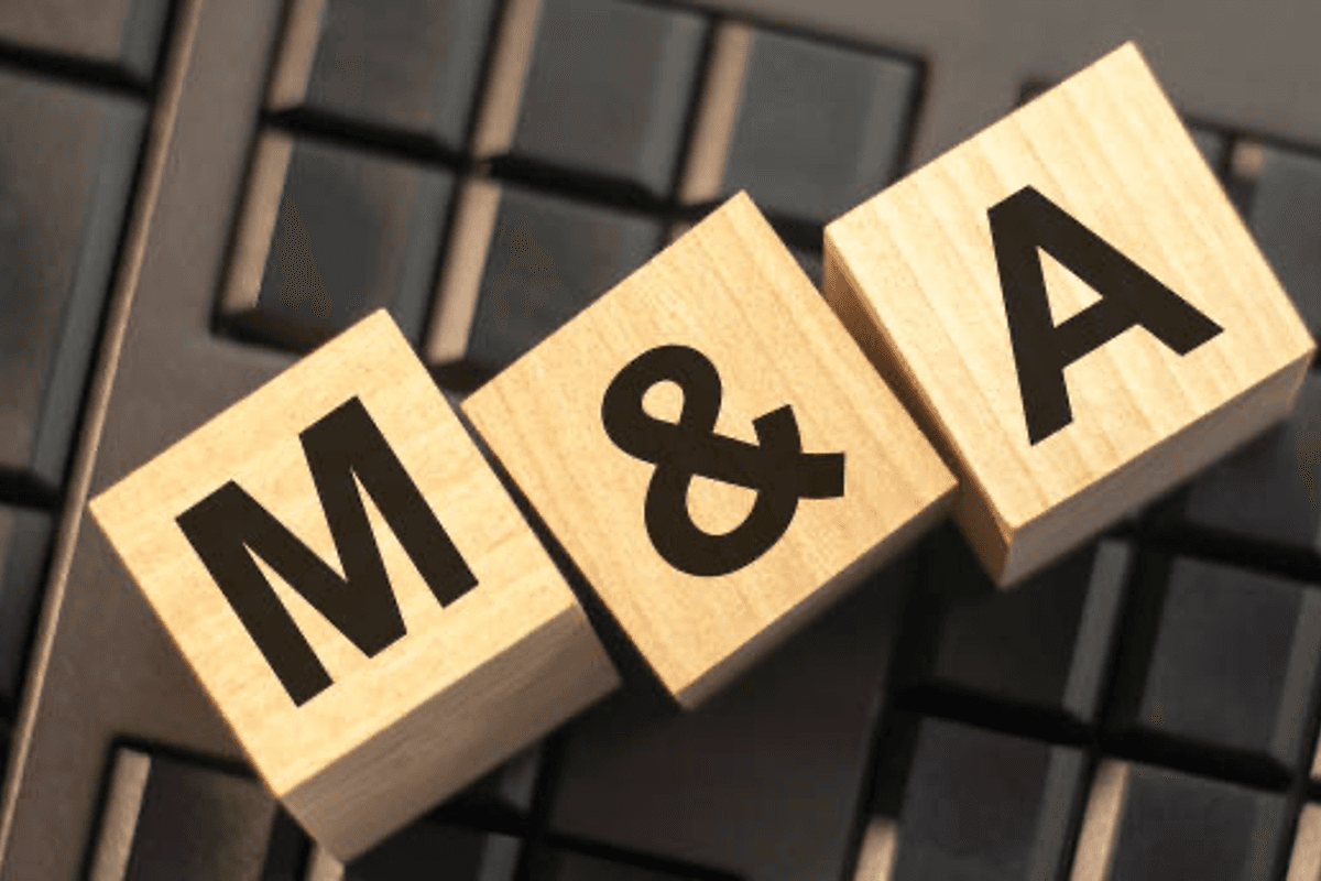 Three wooden blocks with black letters "M&A" rest on a computer keyboard.