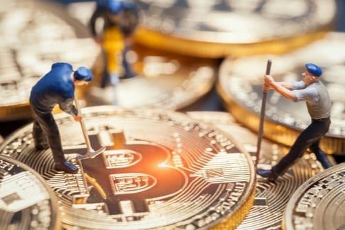 tiny miner figures use pickaxes on physical representations of bitcoin
