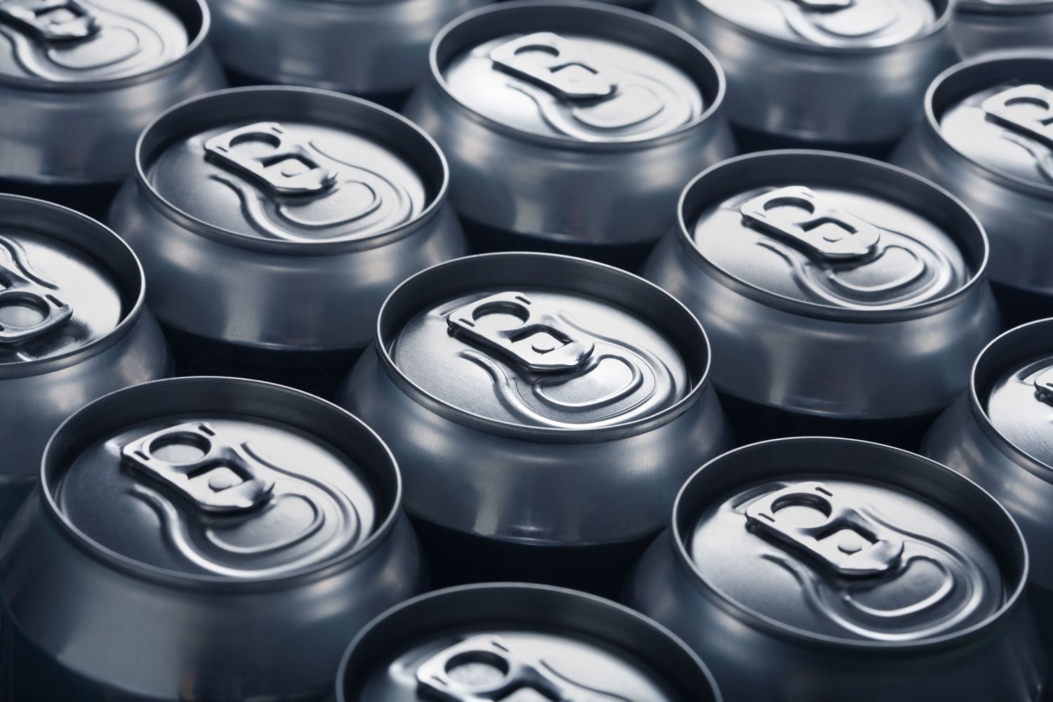 Tops of aluminum beverage cans lined up in rows.