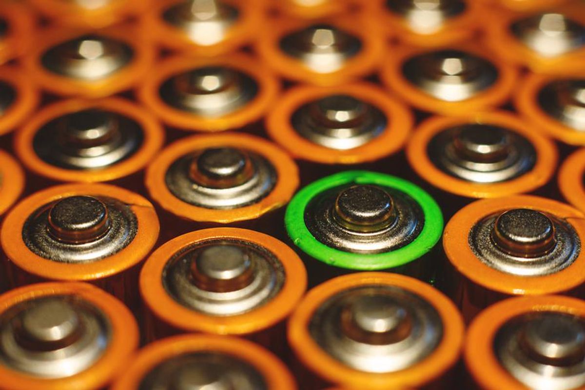 tops of batteries lined up, one has a green ring instead of brown
