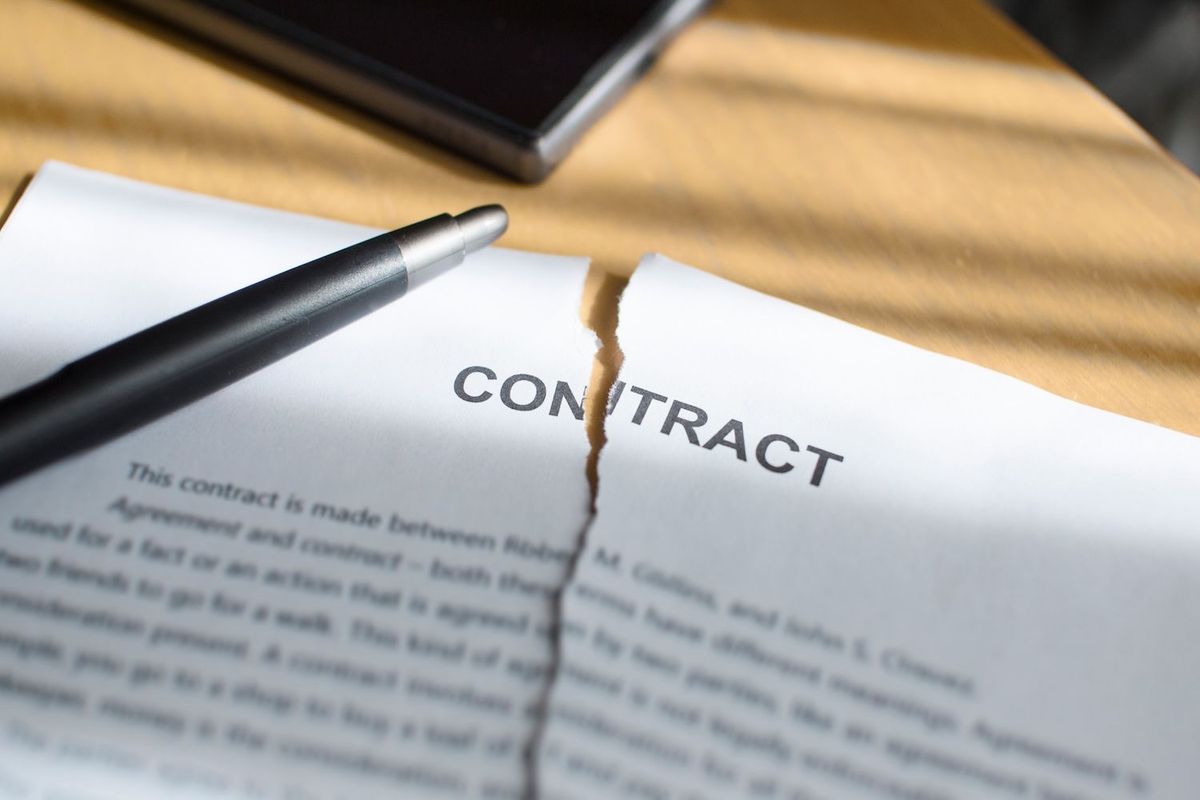 Torn contract paper with a pen on a table.
