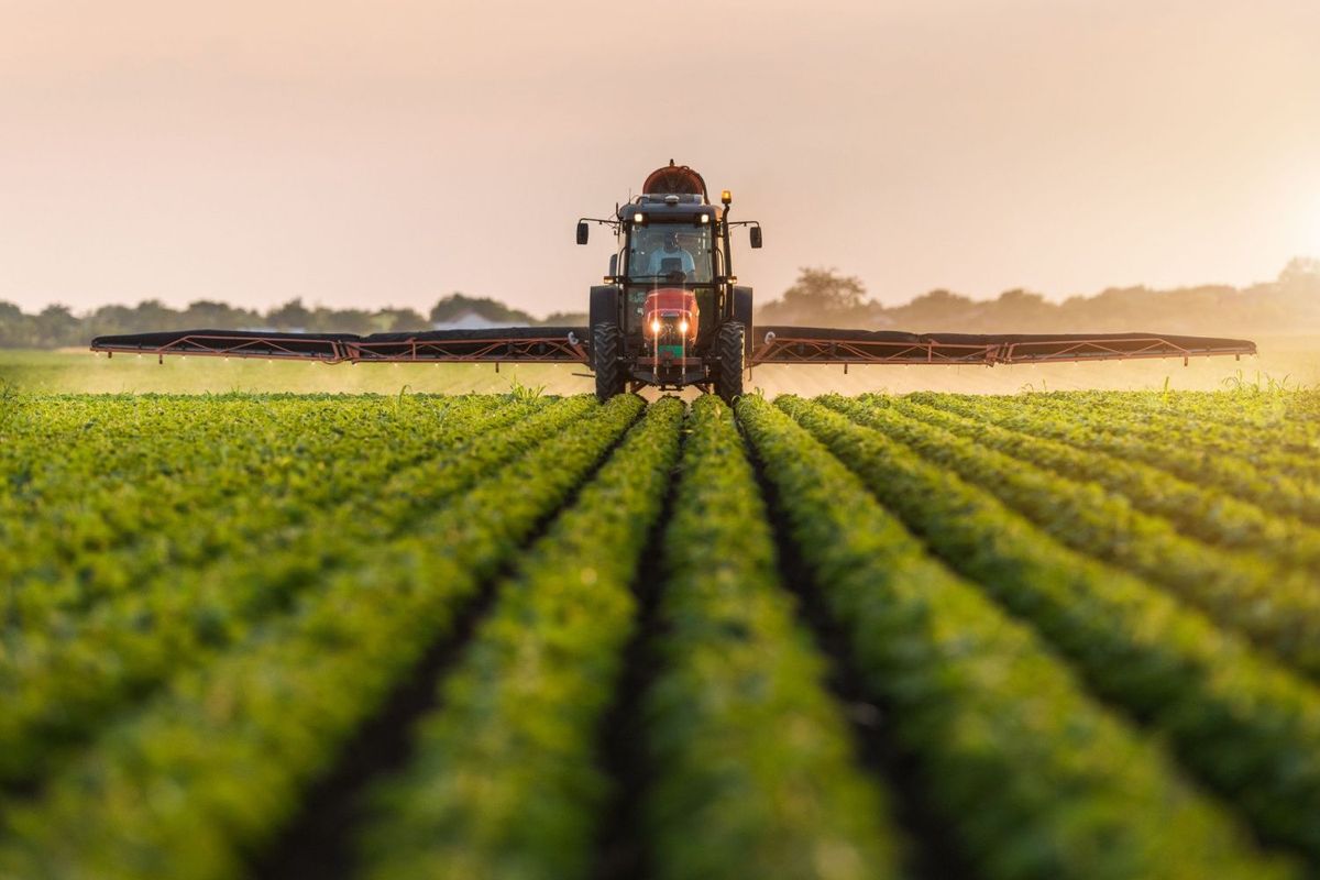 Tractor spraying pesticides in field.
