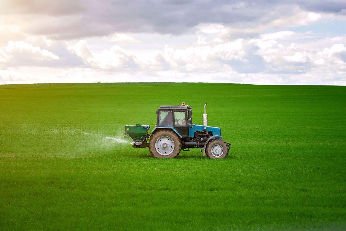 Tractor spreading potash fertilizer on field at farm.