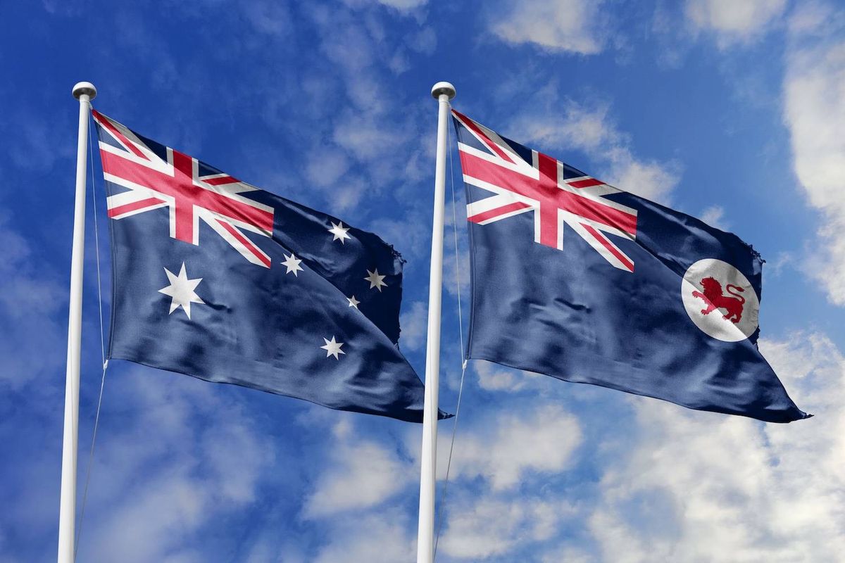Two flags on poles against a blue sky with clouds, showing Australian and Tasmanian designs.