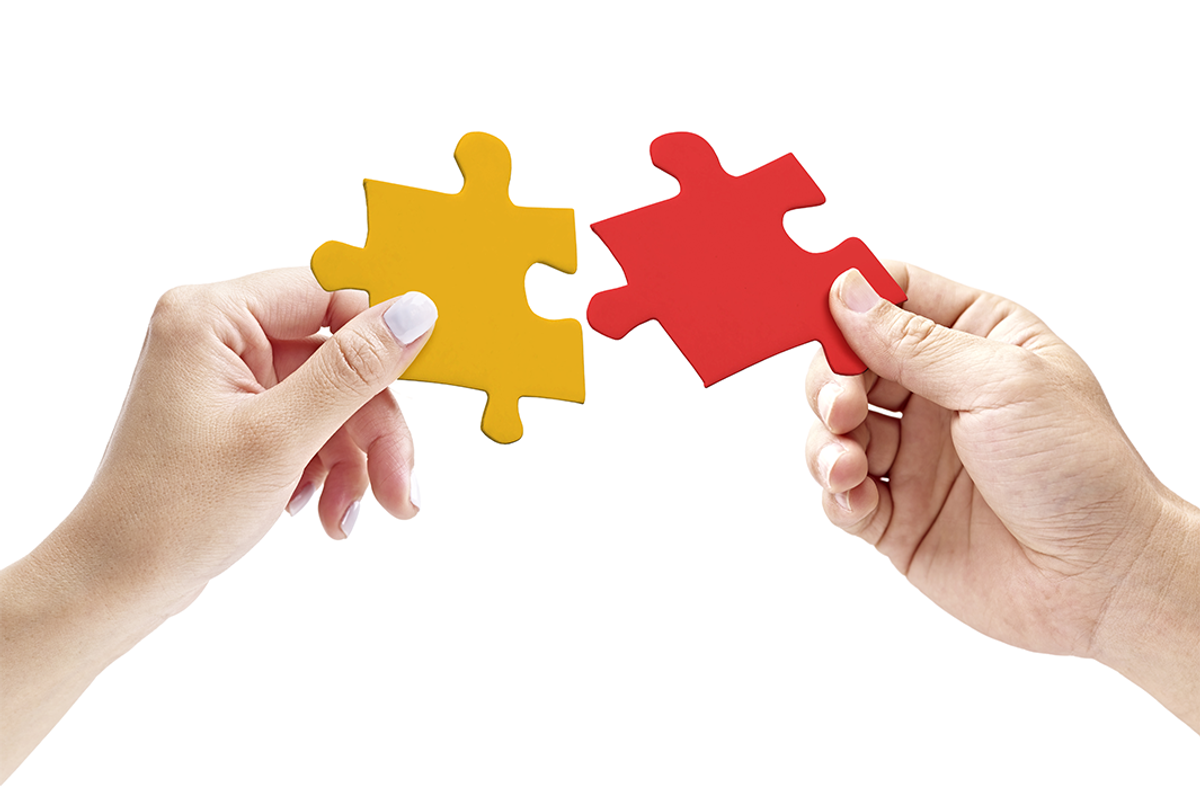 two hands next to one other, each holding a puzzle piece