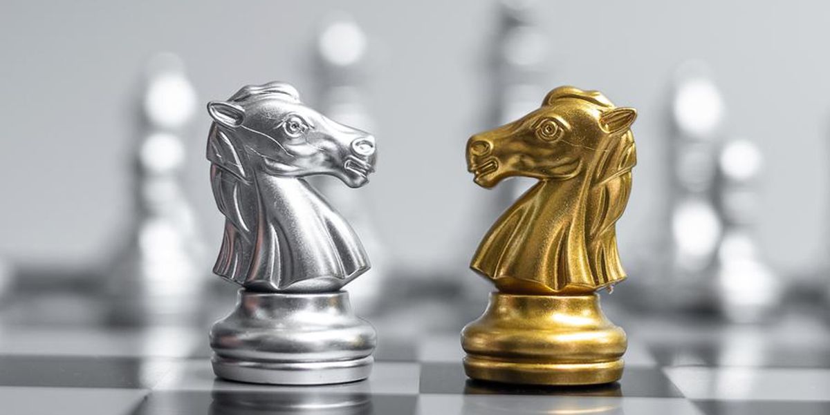 two knight chess pieces on a board facing each other