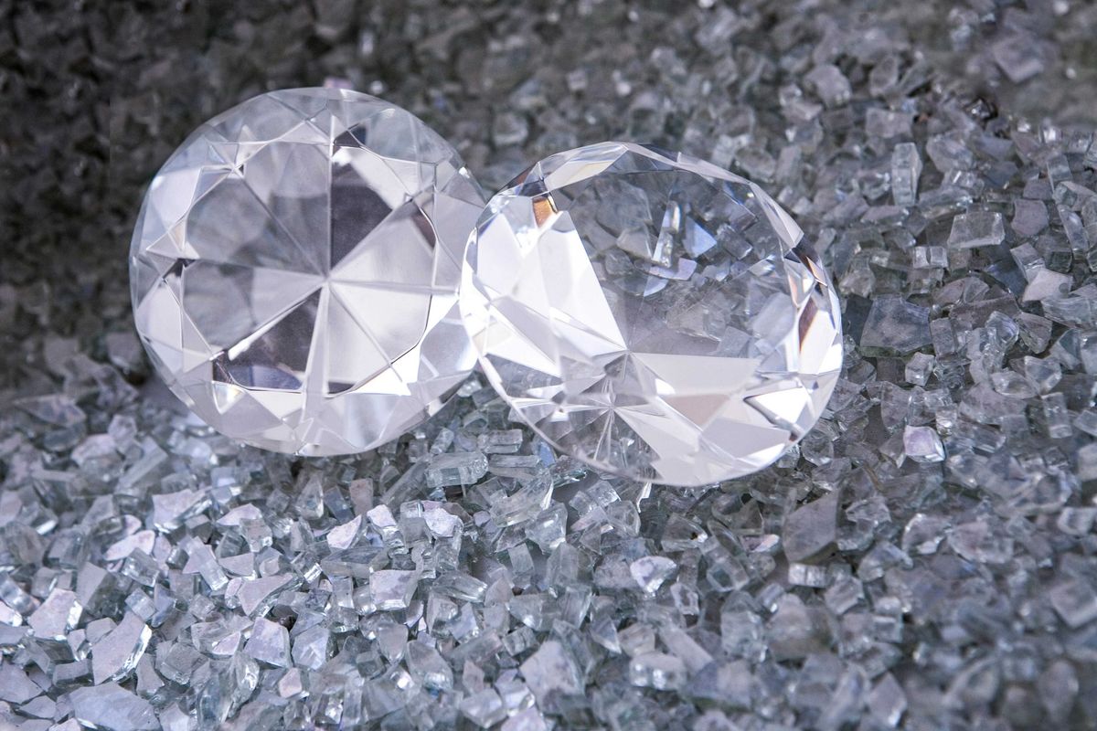 Two large, faceted clear gemstones on a bed of small, shiny crystals.
