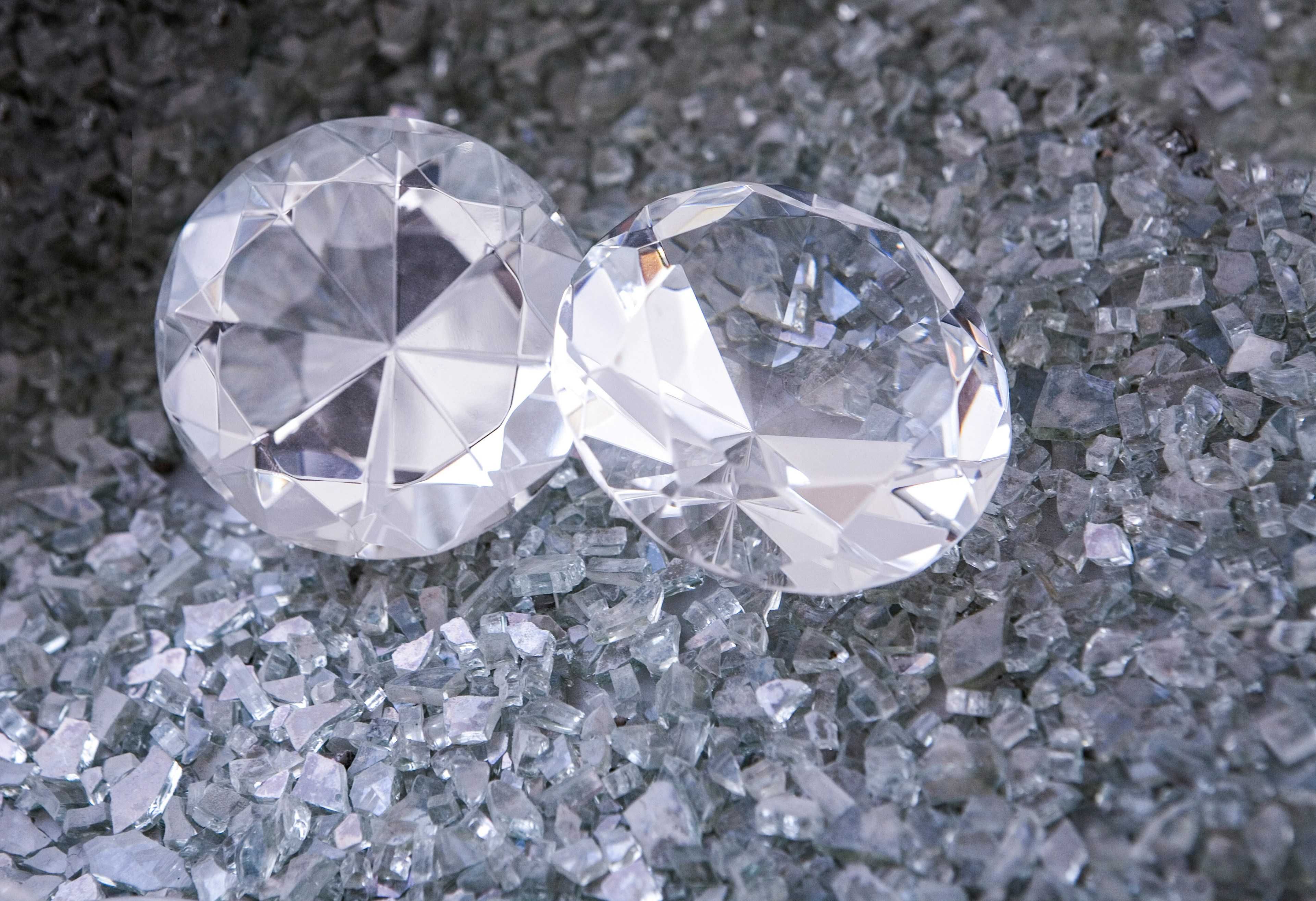 Two large, faceted clear gemstones on a bed of small, shiny crystals.