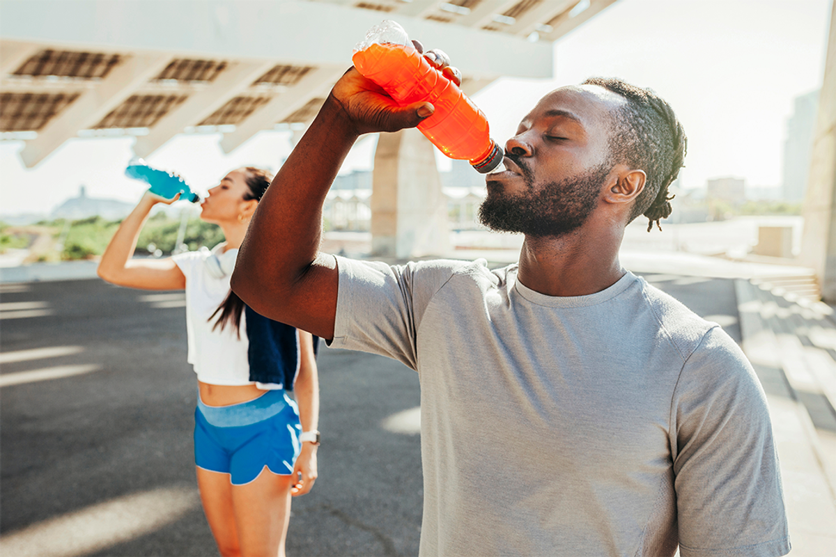 two people drinking different coloured beverages out of water bottles