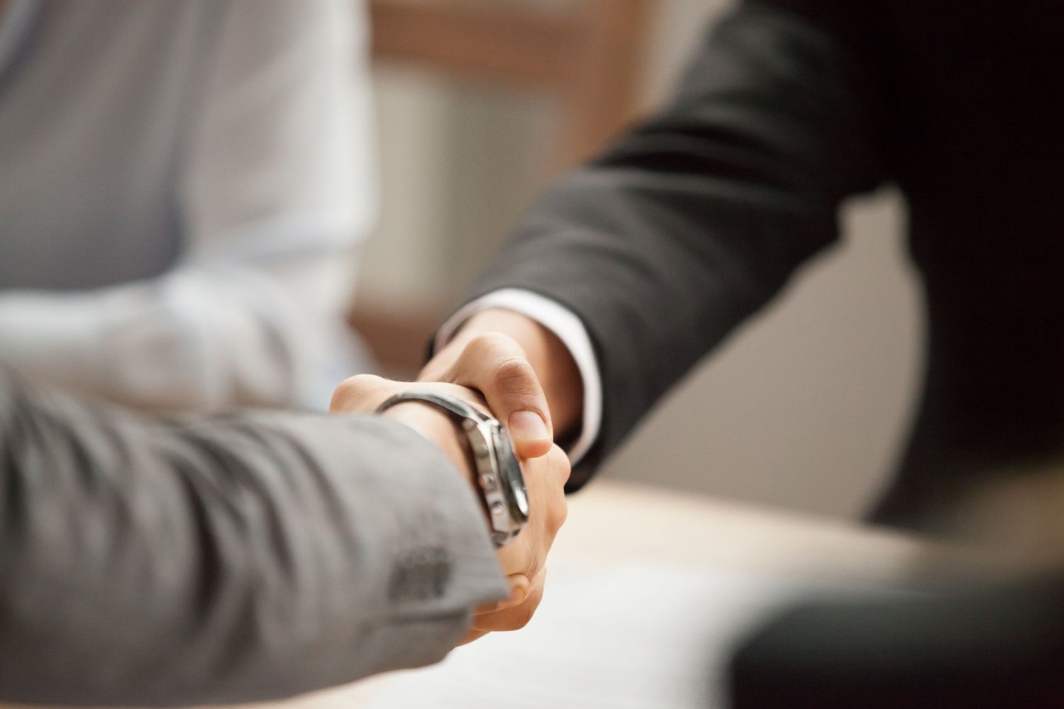 Two people in suits shake hands, agreeing to a deal.