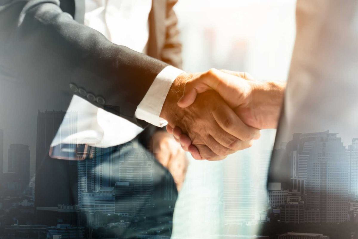 Two people in suits shaking hands, overlaid with a cityscape.