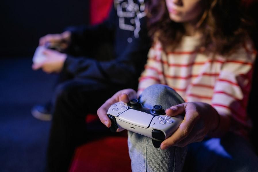 two people playing games, camera is focused on PS5 controller