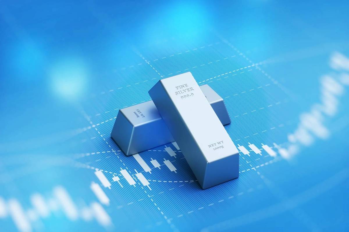 Two silver bars rest on a blue background with white financial chart lines; text reads: FINE SILVER 999.9.