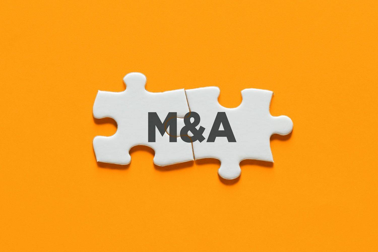 Two white puzzle pieces on an orange background, with text reading: M&A.