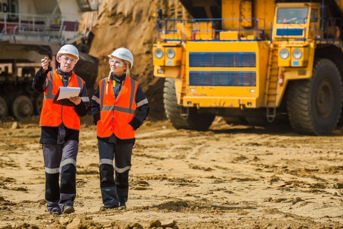 Two workers at mine site with clipboard.