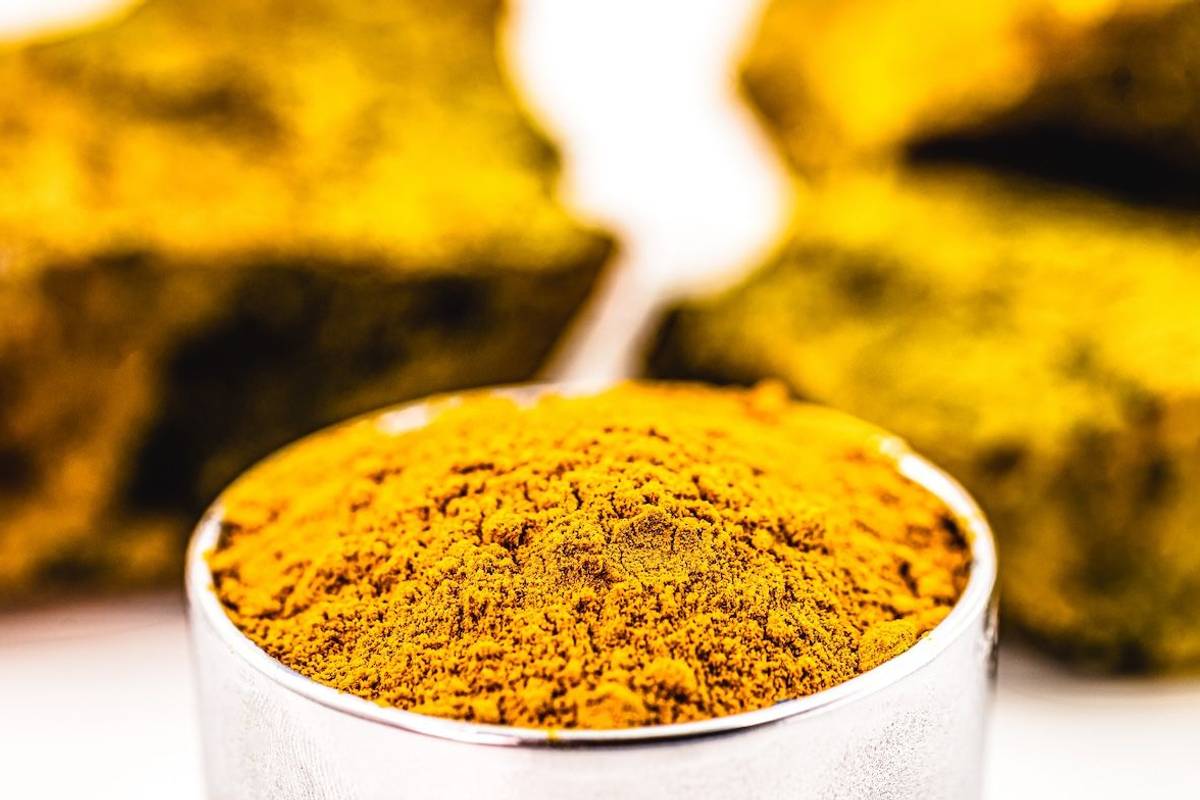 U3O8 yellowcake in a silver cup in front of uranium ore in the background.