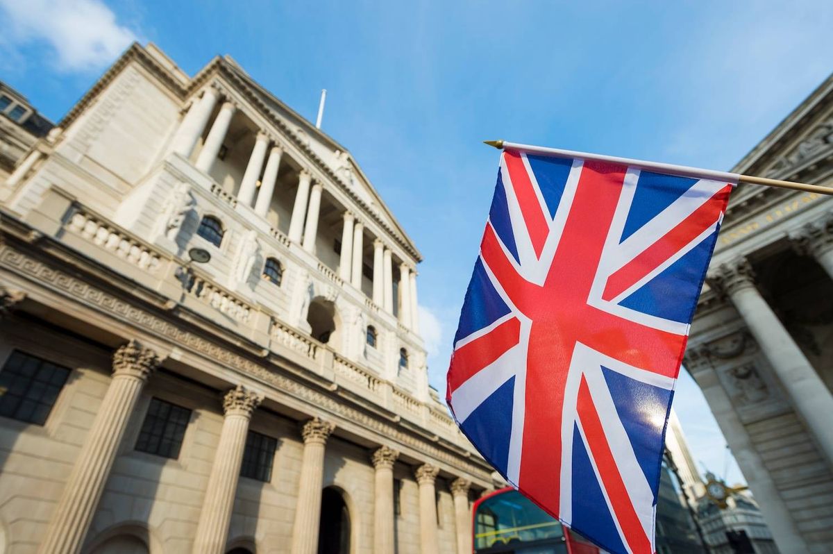 Union Jack flag near historic building with columns under a blue sky.