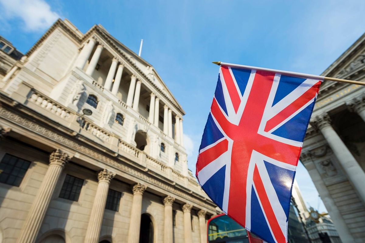 Union Jack flag near historic building with columns under a blue sky.