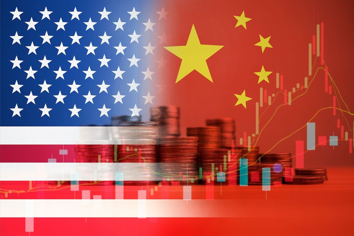 US and China flags with coins and stock market graph overlay.
