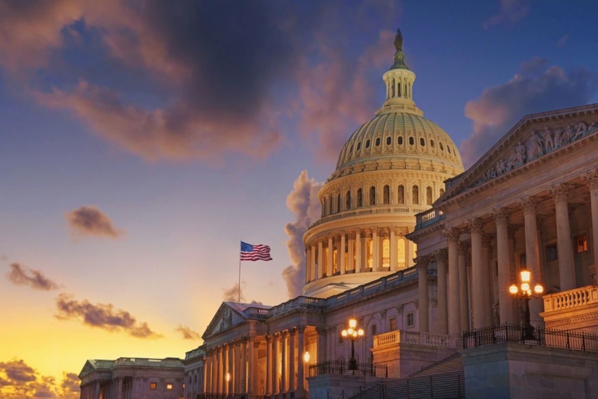 US Capitol at sunset with dramatic clouds and illuminated facade.