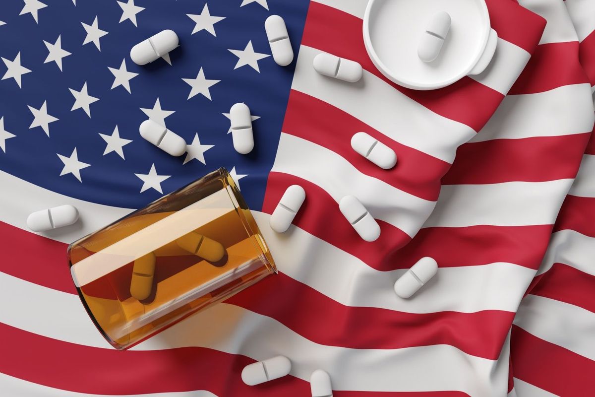 US flag with orange pill bottle on top and white pills spilling out.