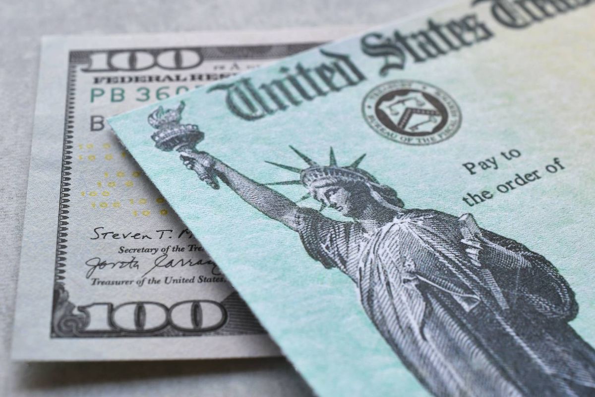 US Treasury check with the Statue of Liberty placed over US$100 bill.