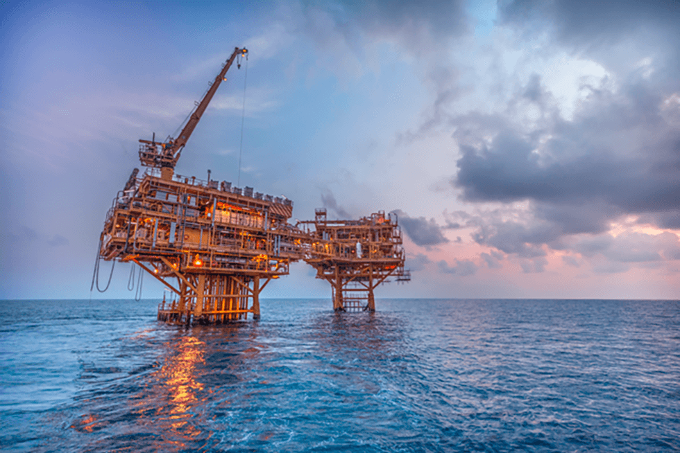 Valeura Energy's offshore oil rig at sunset, surrounded by calm ocean waters under a cloudy sky.