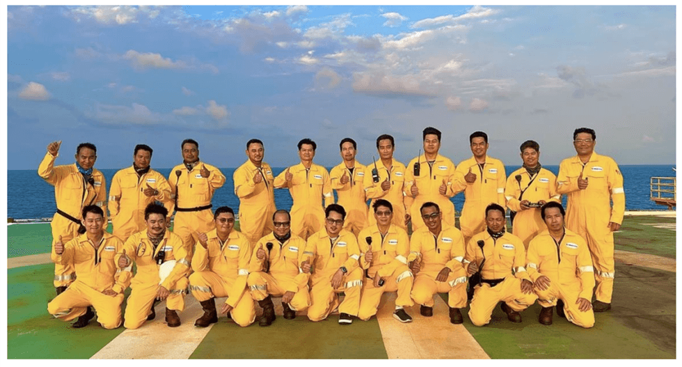 Valeura Energy team posing on a ship deck with the ocean in the background.